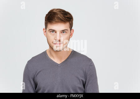 Portrait of serious handsome young man in grey pullover over white background Stock Photo