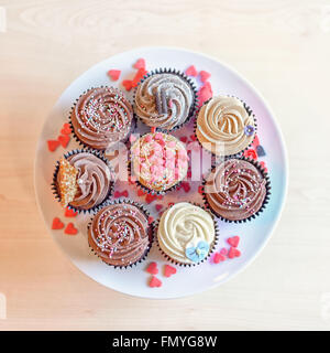 Top down above view on eight deliciously sweet cupcakes covered with creamed chocolate, vanilla and various other garnishments a Stock Photo
