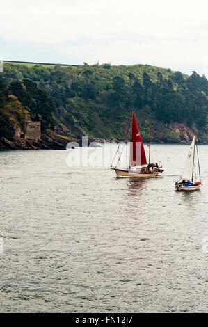 Two small sailing vessels pass each other in different directions opposite the  coastal artillery tower of Kingswear Castle Stock Photo