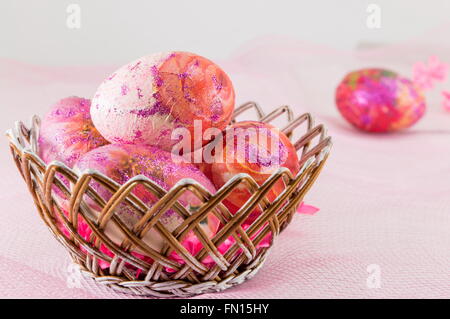 Pink decoupage decorated Easter eggs in a wicker basket Stock Photo