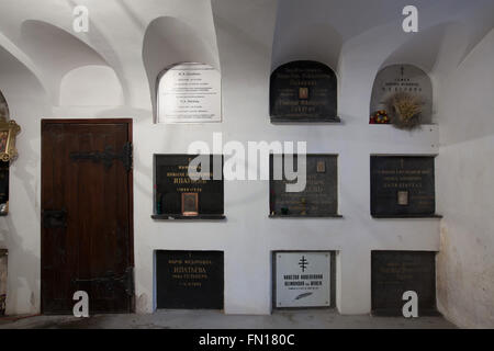 Graves of the most notable persons of the Russian emigration in Czechoslovakia in the underground crypt of the Dormition Church at the Olsany Cemetery in Prague, Czech Republic. Grave of engineer Nikolai Ipatiev, who was an owner of the notoriously Ipatiev House in Yekaterinburg, Russia, where Tsar Nicholas II and his family were murdered in July 1918 by the Bolsheviks, is seen in the left in the middle. Graves in the upper line from left to right: former burial place of Russian historian Fyodor Shcherbina, who was reburied to Russia, Russian general Vladimir Shokorov, Russian doctor Nikolai K Stock Photo