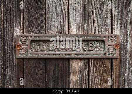 Old rusted mailbox in dark brown wooden door. Text Lettere in Italian means Letters Stock Photo