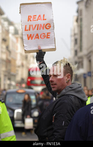 London, UK. 12th March 2016. Cleaners contracted to work at Topshop clothing store protest outside the flagship branch on Oxford Circus to demand a raise in pay to the London Living Wage of £9.40/hr.  Protesters stop traffic as they march down Oxford Street. Credit:  Denis McWilliams/Alamy Live News