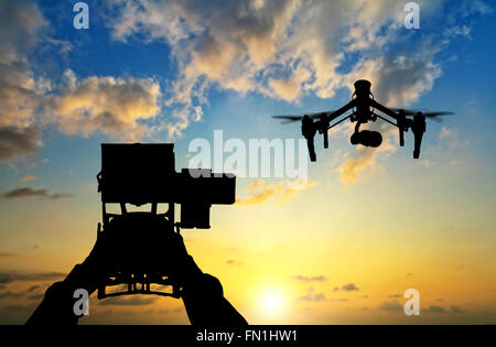 Man hands handling drone in sunset silhouettes Stock Photo