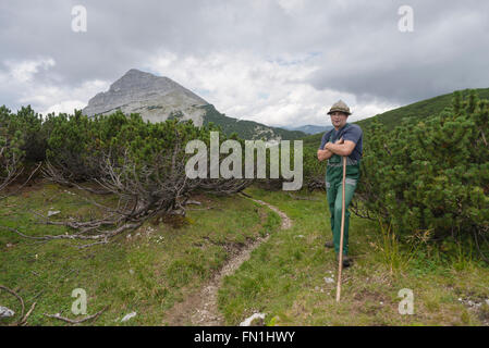 Portrait of a mountain farmer between mountain pines in front of the summit of Mount Guffert, Rofan, Tirol, Austria Stock Photo