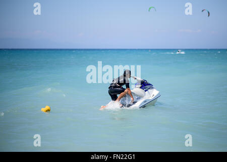 A guy getting on a water scooter in the sea Stock Photo