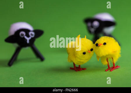 A close-up image of a pair of easter chicks being watched by a of duo of miniature lambs. Stock Photo