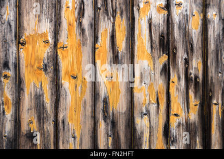 Vertical board wall in gray and black with remains of yellow paint. Taken as a background in close-up. Stock Photo