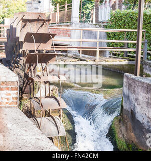 Old iron wheel a watermill. Ruins of a watermill. Stock Photo