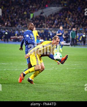 KYIV, UKRAINE - NOVEMBER 15, 2013: Roman Zozulya of Ukraine (in Yellow) fights for a ball with Eric Abidal of France during thei Stock Photo