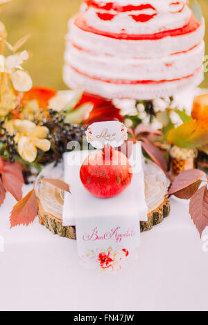 Big red pomegranate close up with wedding cake on background Stock Photo