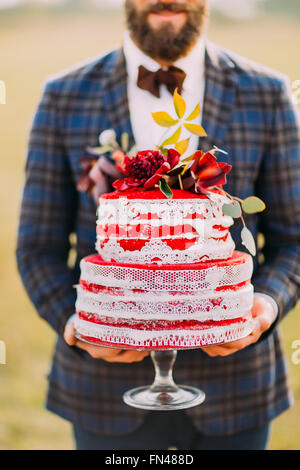 Stylish bearded groom with delicious wedding cake in hands closeup Stock Photo