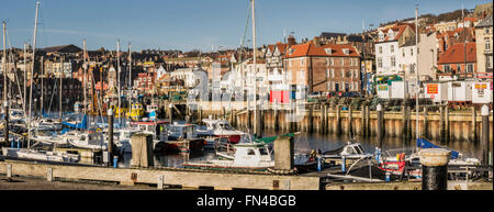 View across Scarborough Harbour with boats. Looking towards seafront shops and amusement arcades. Stock Photo