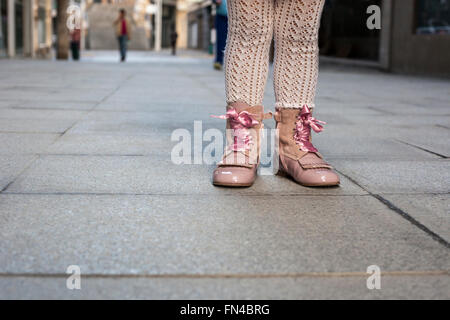 Happy three year old girl wearing pink satin lace boots on the city. Close up Stock Photo