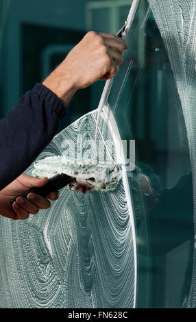 Window cleaner using a squeegee to wash a window Stock Photo