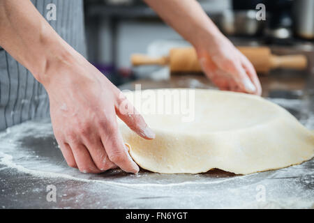 Hands of man preparing pie in baking pan on the kitchen