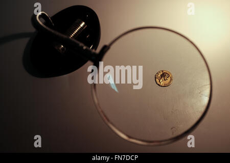 Jerusalem, Israel. 14th March, 2016. A rare gold coin bearing the image of Emperor Augustus is viewed through a magnifying glass. Minted in Rome in 107 CE, the coin was part of a series minted by Emperor Trajan as a tribute to Roman emperors that preceded him. The coin, discovered by a hiker in Israel’s North, is an identical twin to a coin owned by the British Museum and until now believed to be the only one of its kind known in the world. Credit:  Nir Alon/Alamy Live News Stock Photo