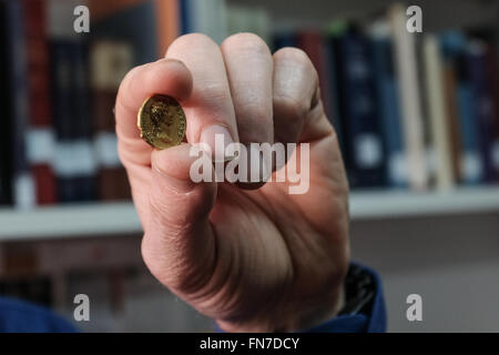 Jerusalem, Israel. 14th March, 2016. Dr. DONALD ARIEL, Head Curator of the Coin Department at the Israel Antiquities Authority, holds a rare gold coin bearing the image of Emperor Augustus. Minted in Rome in 107 CE the coin was part of a series minted by Emperor Trajan as a tribute to Roman emperors that preceded him. The coin, discovered by a hiker in Israel’s North, is an identical twin to a coin owned by the British Museum and until now believed to be the only one of its kind known in the world. Credit:  Nir Alon/Alamy Live News Stock Photo