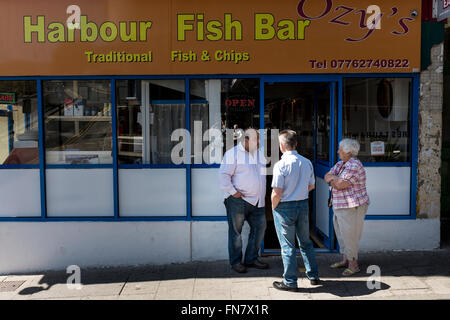 Three people (two men and a woman) talking outside of a fish and chips shop, Ramsgate, Kent, UK Stock Photo