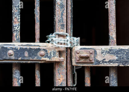 Old wooden and rusty metal gate with peeling paint chained up with a new chain, England, UK Stock Photo