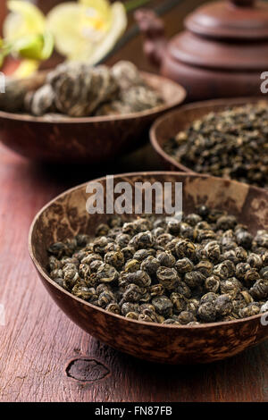 different types of green tea in bowls, a teapot on a wooden background (dark) Stock Photo