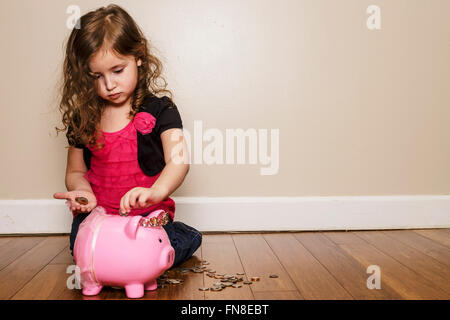 little girl putting money in her piggy bank Stock Photo