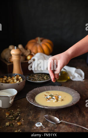 Boy seasoning bowl of potato soup Stock Photo