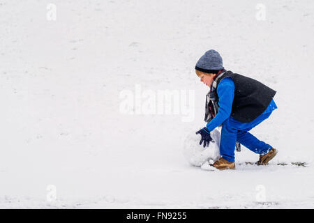 Boy rolling snow ball for making a snowman Stock Photo