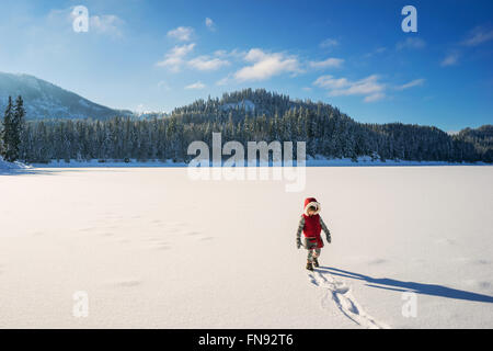 Young girl walking on snow covered lake Stock Photo