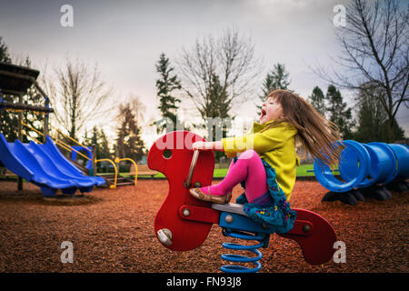 Girl sitting on spring ride in playground Stock Photo