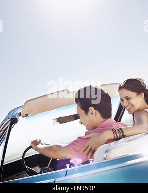A young couple, man and woman in a pale blue convertible on the open road Stock Photo