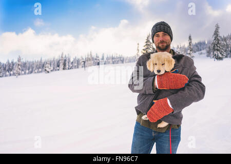 Man holding golden retriever puppy dog in his coat Stock Photo
