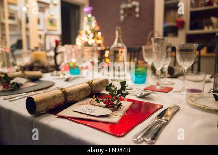 A table laid for a Christmas meal, with silver and crystal glasses and a Christmas tree in the background. Stock Photo