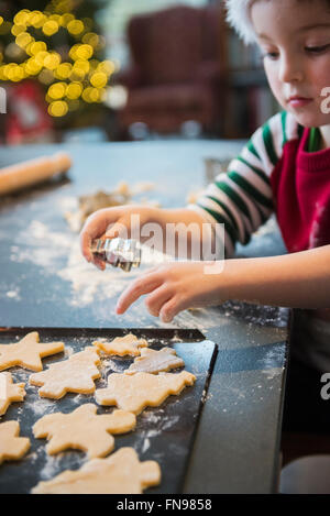 A boy in a Santa hat making Christmas biscuits, cutting out shapes. Stock Photo