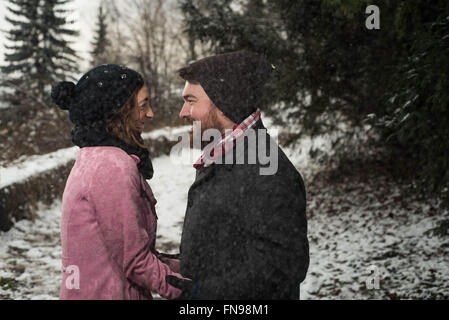 Couple standing in forest in snow Stock Photo
