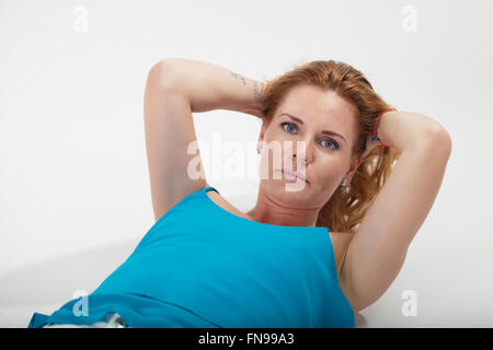 Woman lying on floor with hands behind her head Stock Photo