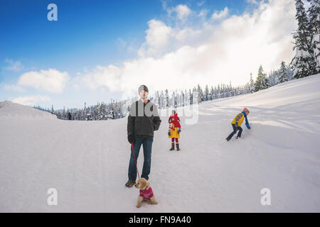 Father with three children and a golden retriever puppy dog in snow