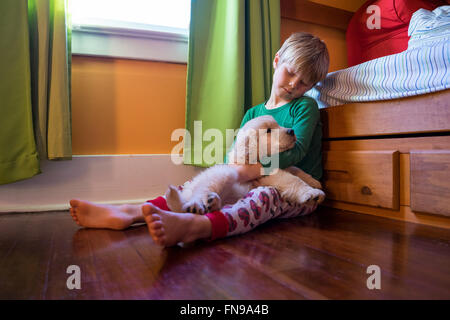 Boy sitting on floor with golden retriever puppy dog Stock Photo