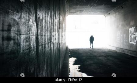 Silhouette of a man walking through tunnel Stock Photo