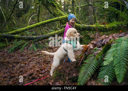 Young girl and golden retriever puppy dog digging in the forest Stock Photo