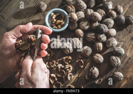 Close up of a senior woman cracking walnuts Stock Photo