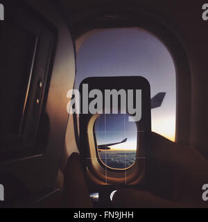 Person taking photo on airplane with mobile phone Stock Photo