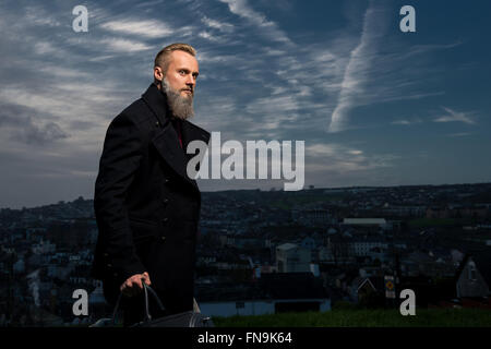 Hipster man standing in park with bag Stock Photo