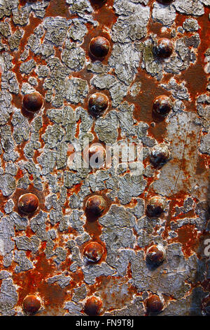 Grunge background with patterns and textures of flaking paint on rusty metal with rivets. Stock Photo