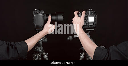 Two angle of Black digital camera on black background with photographer hand pushing the button Stock Photo