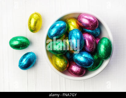 Chocolate eggs in bowl on wooden table, top view Stock Photo