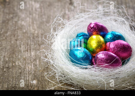 Chocolate eggs in nest on wooden table Stock Photo