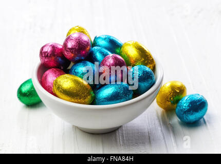 Chocolate eggs in bowl on wooden table Stock Photo
