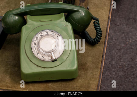 Old vintage rotary dial green telephone on a market stall at carboot sale in Bath, UK. Stock Photo