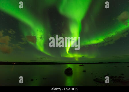 Aurora Beams - Three bright aurora beams scanning through the starry night sky over a lake. Stock Photo